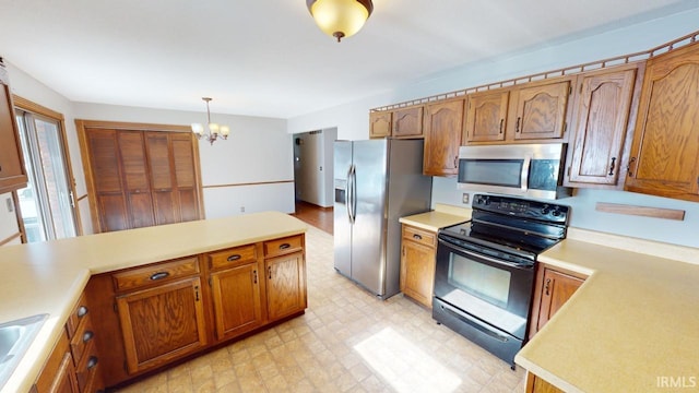 kitchen featuring stainless steel appliances, sink, a notable chandelier, and hanging light fixtures