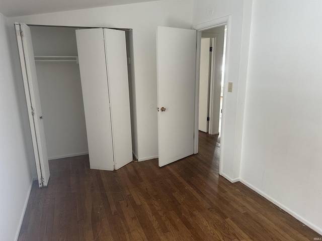 unfurnished bedroom with dark wood-type flooring, a closet, and vaulted ceiling