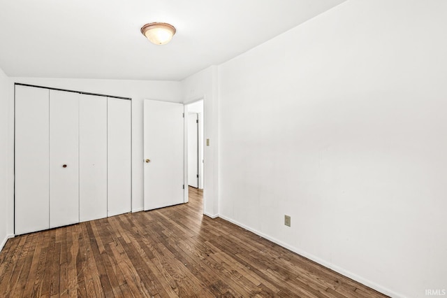 unfurnished bedroom featuring hardwood / wood-style flooring, lofted ceiling, and a closet