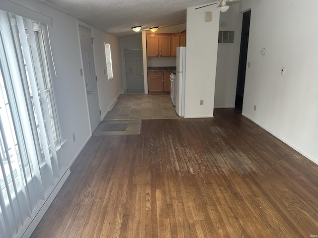 unfurnished living room featuring a textured ceiling, ceiling fan, vaulted ceiling, and dark hardwood / wood-style floors