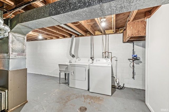 basement featuring sink, heating unit, and independent washer and dryer