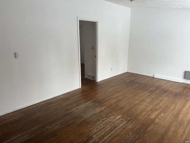 empty room featuring a baseboard heating unit, dark hardwood / wood-style flooring, and a textured ceiling