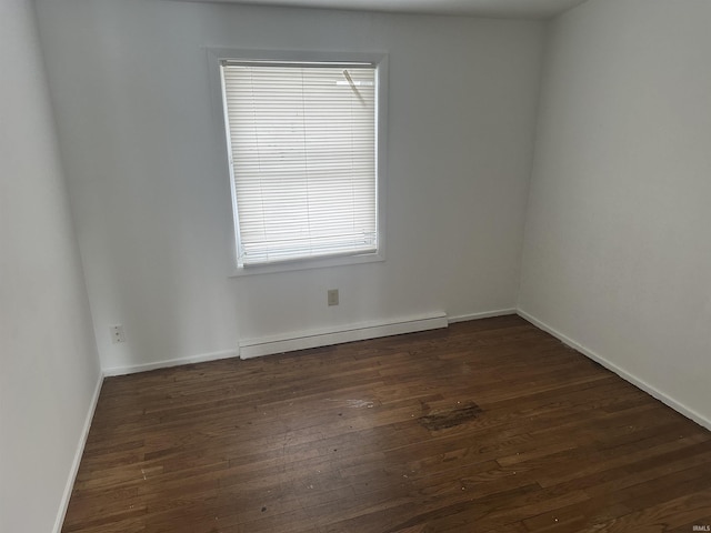 unfurnished room with a baseboard heating unit and dark hardwood / wood-style floors