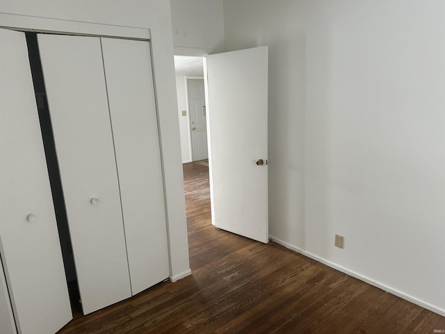 unfurnished bedroom with dark wood-type flooring and a closet