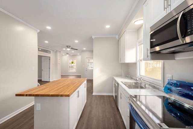 kitchen featuring wooden counters, stainless steel appliances, white cabinetry, and sink