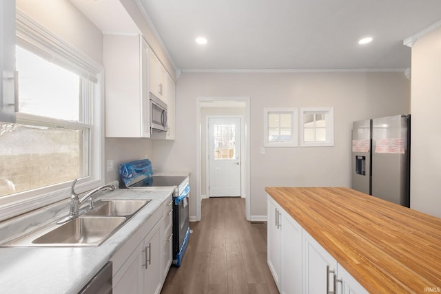 kitchen featuring stainless steel appliances, a wealth of natural light, hardwood / wood-style flooring, white cabinets, and sink