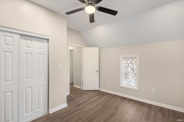 unfurnished bedroom featuring lofted ceiling, dark hardwood / wood-style flooring, a closet, and ceiling fan