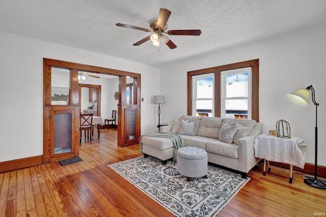 living room with a textured ceiling, ceiling fan, and hardwood / wood-style flooring