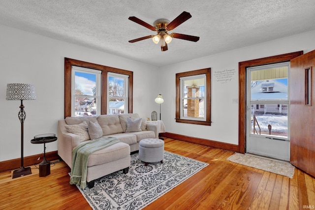 living room featuring a textured ceiling, ceiling fan, and light wood-type flooring