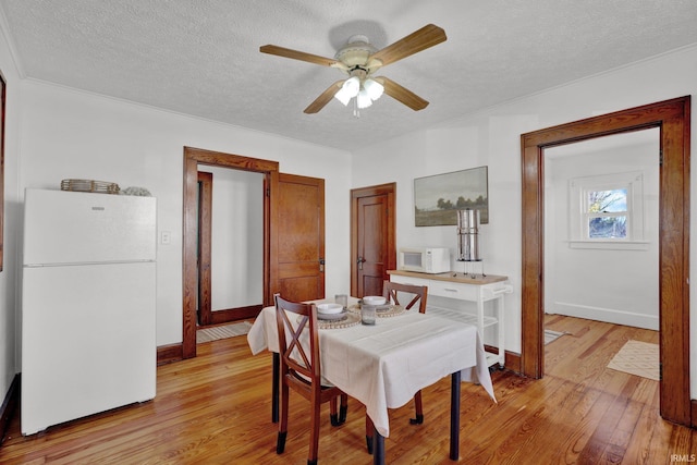 dining room with a textured ceiling, light wood-type flooring, and ceiling fan