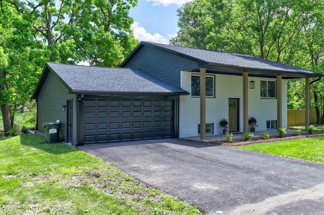 2444 Clover Cir, Newburgh, IN 47630 - raised ranch featuring brick siding, a garage, roof with shingles, a front yard, and asphalt driveway