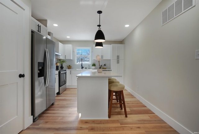 kitchen featuring pendant lighting, a center island, stainless steel appliances, a breakfast bar, and white cabinetry