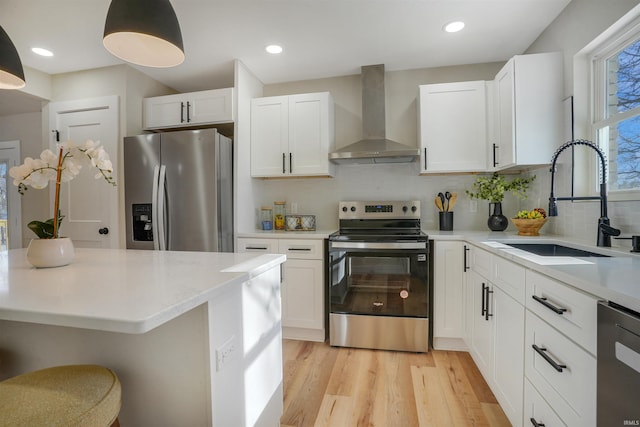 kitchen featuring stainless steel appliances, wall chimney exhaust hood, sink, white cabinetry, and backsplash