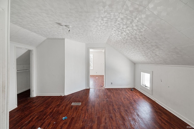 additional living space with vaulted ceiling and dark hardwood / wood-style floors