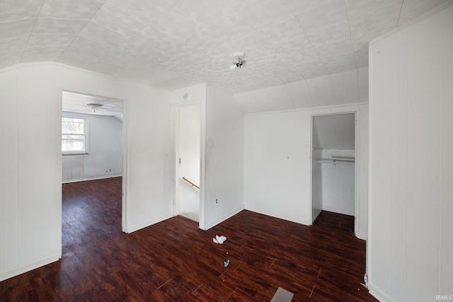 unfurnished bedroom featuring dark wood-type flooring, vaulted ceiling, and a closet