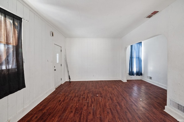 empty room featuring wood walls and wood-type flooring