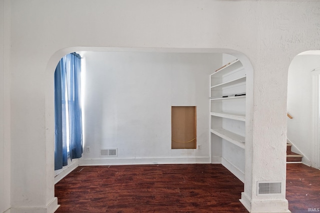 spare room with built in features and dark hardwood / wood-style floors