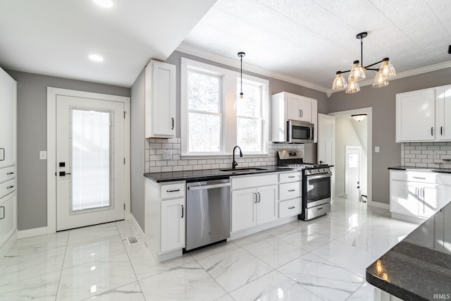 kitchen featuring sink, white cabinets, hanging light fixtures, and appliances with stainless steel finishes