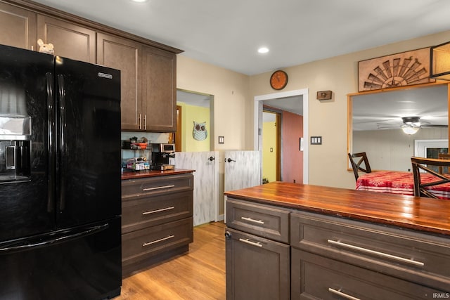 kitchen with light hardwood / wood-style flooring, black refrigerator with ice dispenser, butcher block countertops, ceiling fan, and dark brown cabinets