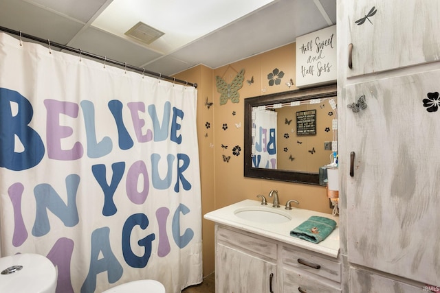 bathroom featuring toilet, a paneled ceiling, and vanity