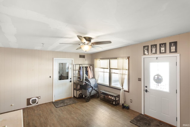 entryway featuring wood-type flooring, wood walls, and ceiling fan