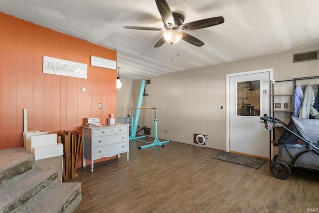 interior space with wood walls, hardwood / wood-style floors, and ceiling fan