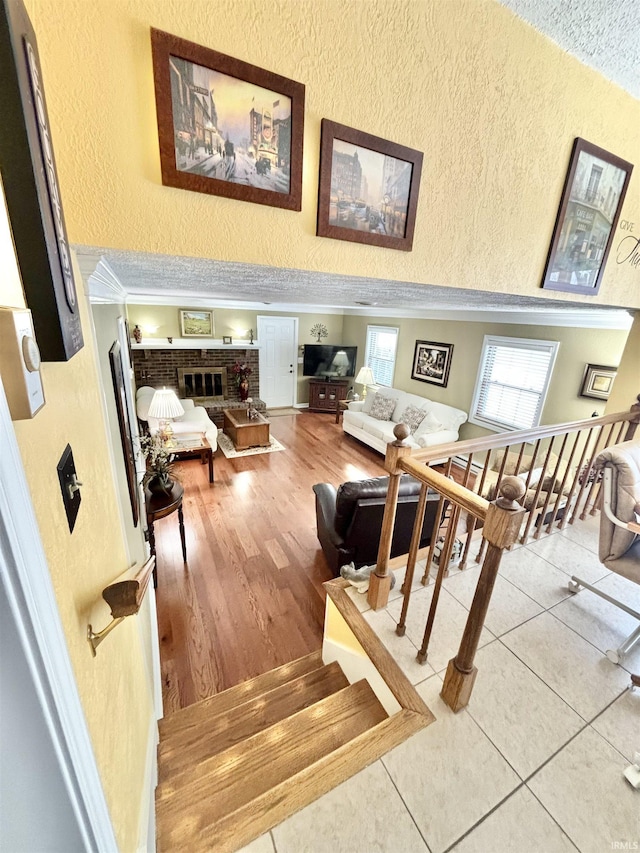 interior space with a brick fireplace, ornamental molding, and light tile patterned floors