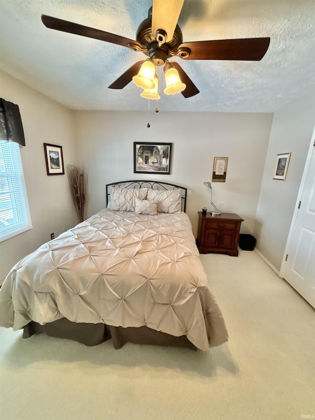 bedroom with a textured ceiling, ceiling fan, and carpet