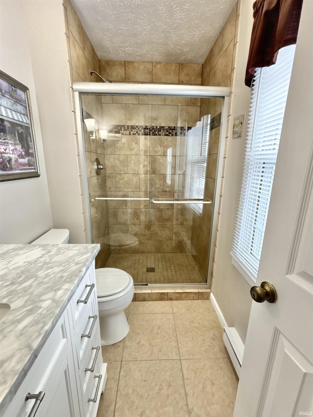 bathroom featuring a textured ceiling, toilet, walk in shower, tile patterned floors, and vanity