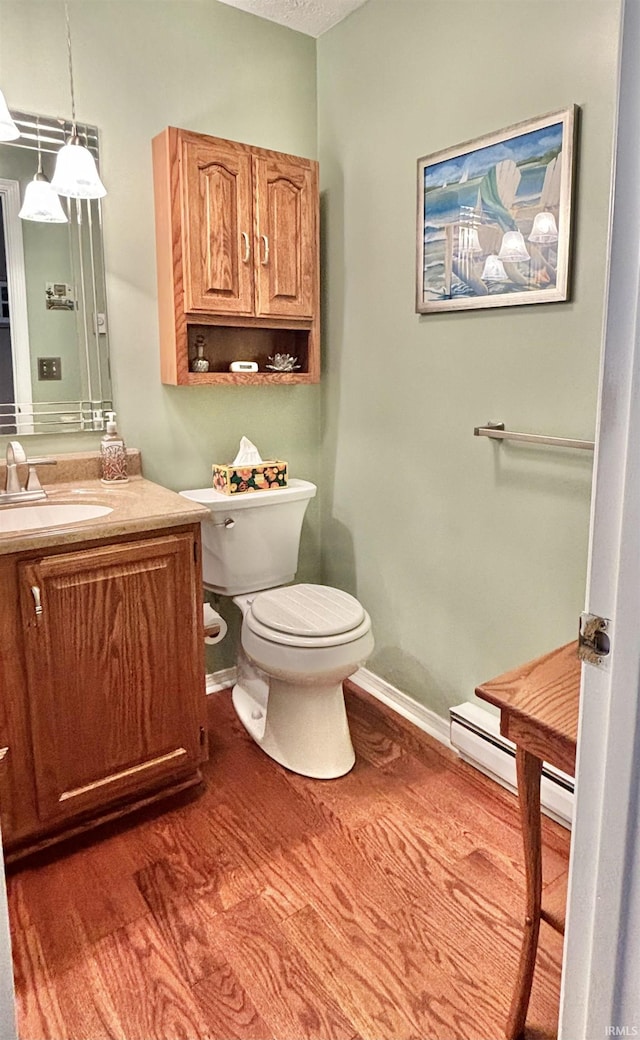 bathroom featuring toilet, vanity, a baseboard radiator, and hardwood / wood-style floors