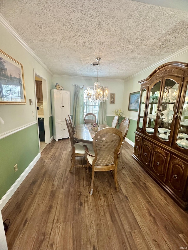 dining room with ornamental molding, dark wood-type flooring, a notable chandelier, and a textured ceiling