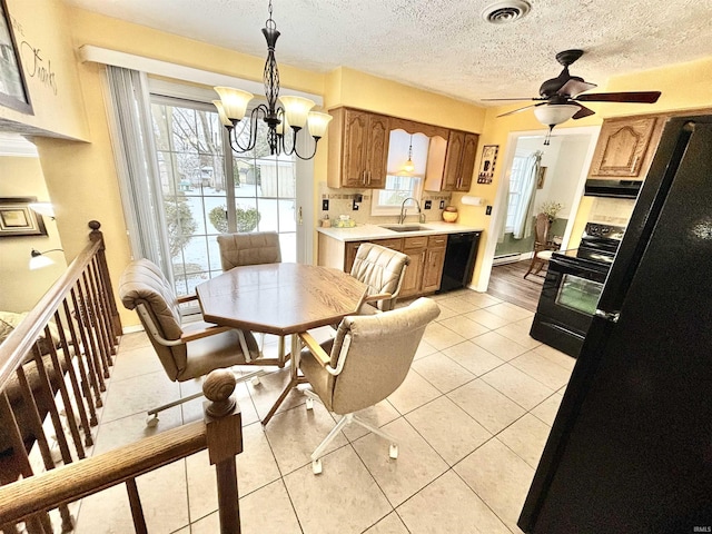 dining room with light tile patterned floors, a textured ceiling, a baseboard heating unit, sink, and ceiling fan with notable chandelier