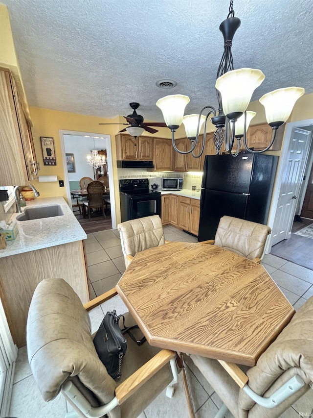 dining area featuring sink, a textured ceiling, ceiling fan with notable chandelier, and light tile patterned floors