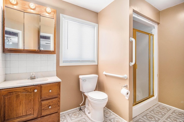 bathroom with toilet, vanity, a shower with shower door, and backsplash