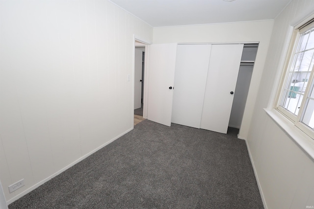 unfurnished bedroom featuring dark carpet, a closet, and multiple windows