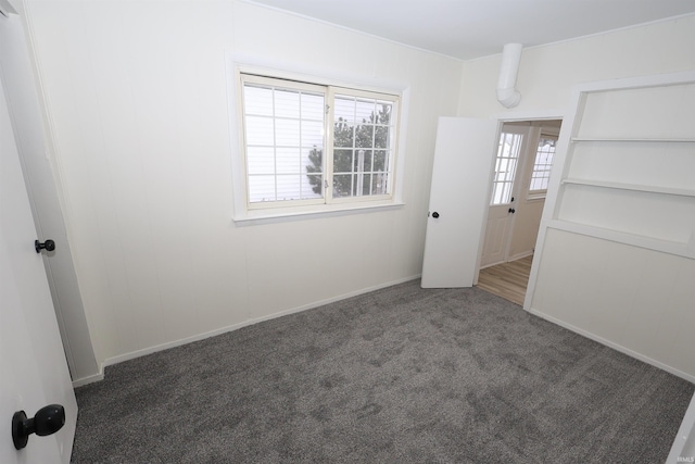 unfurnished bedroom featuring multiple windows and dark colored carpet