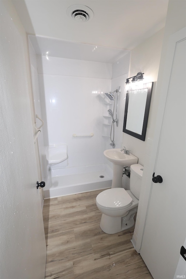 bathroom featuring toilet, wood-type flooring, and walk in shower