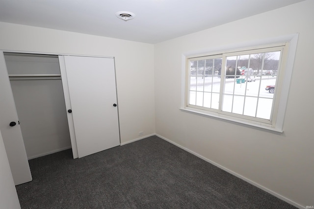 unfurnished bedroom with a closet and dark colored carpet