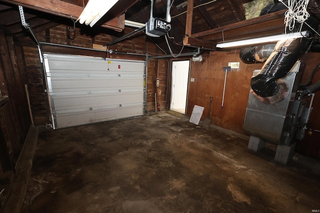 garage featuring a garage door opener, wooden walls, and heating unit