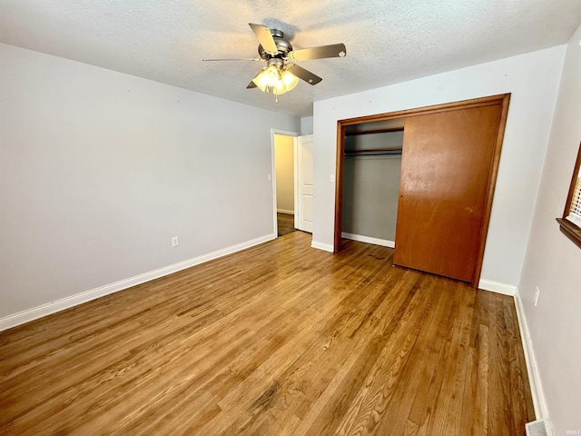 unfurnished bedroom with ceiling fan, light hardwood / wood-style flooring, a closet, and a textured ceiling