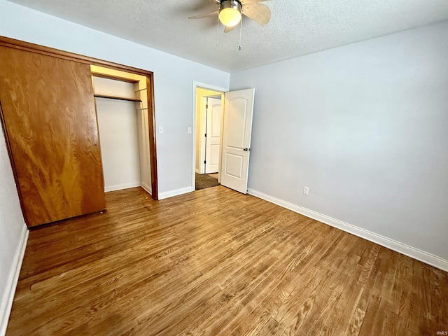 unfurnished bedroom with a textured ceiling, ceiling fan, a closet, and hardwood / wood-style floors