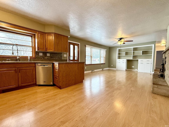 kitchen with a textured ceiling, dishwasher, light hardwood / wood-style flooring, and sink