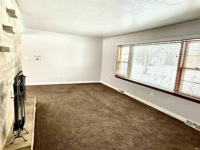 unfurnished living room featuring a fireplace, a textured ceiling, dark colored carpet, and ornamental molding