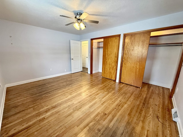 unfurnished bedroom featuring a textured ceiling, two closets, ceiling fan, and light hardwood / wood-style flooring