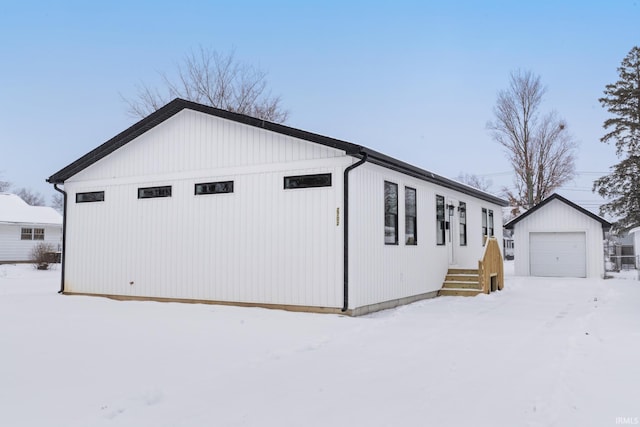 snow covered property featuring an outbuilding and a garage