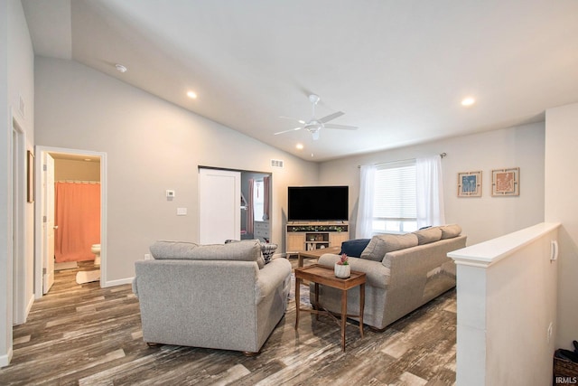 living room with dark hardwood / wood-style flooring, ceiling fan, and vaulted ceiling