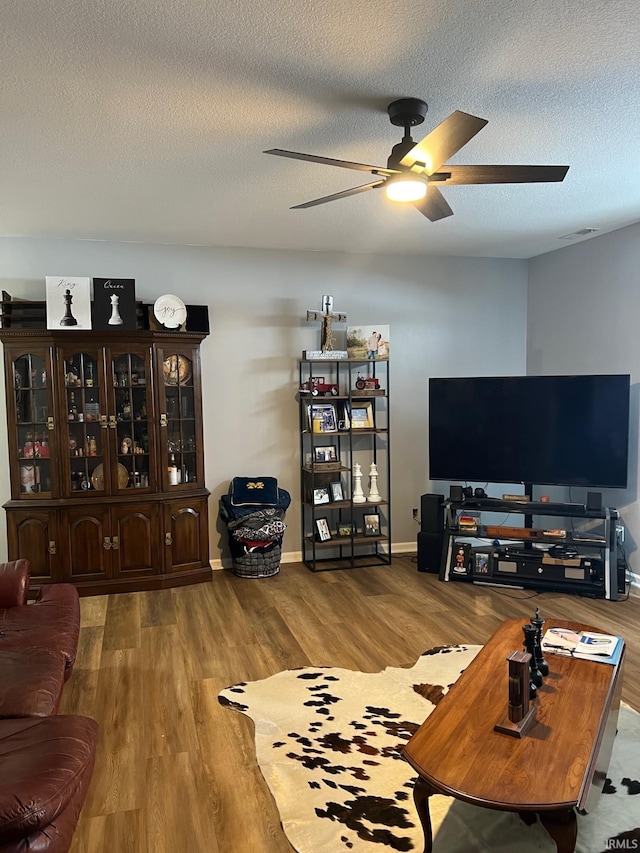 living room featuring ceiling fan, hardwood / wood-style floors, and a textured ceiling