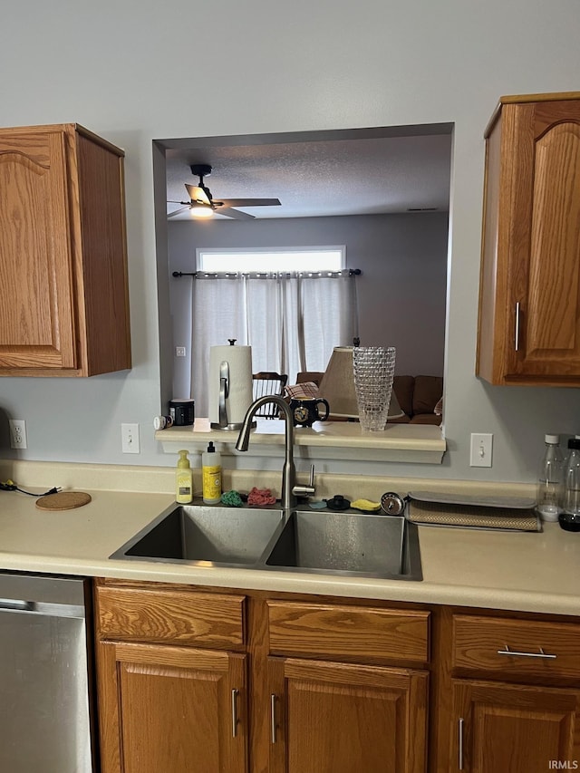 kitchen with sink, a textured ceiling, stainless steel dishwasher, and ceiling fan