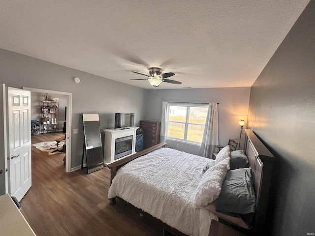 bedroom with ceiling fan, dark hardwood / wood-style floors, and a textured ceiling