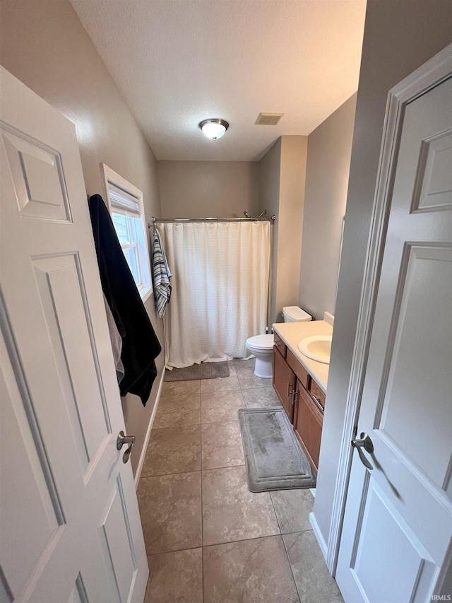 bathroom featuring vanity, tile patterned flooring, a textured ceiling, and toilet